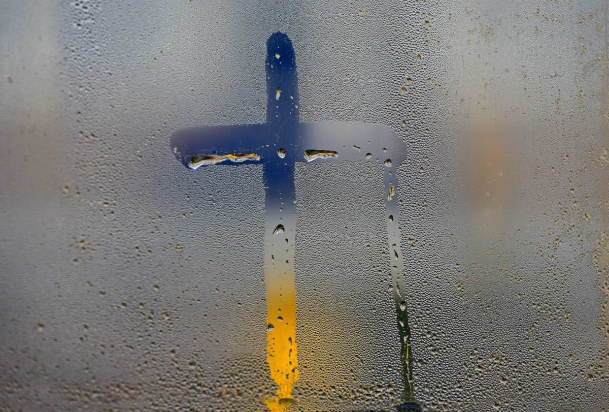 A wet fogged out window with a Christian cross drawn through the condensation—suggestive of the ocean of truth found by those that fall into God.