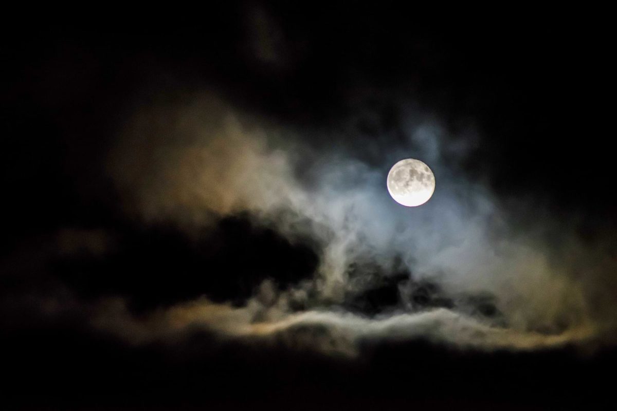 A pale-white moon protruding through the cloud cover, lighting its wooly form amongst the darkness of night—symbolism for a restless mind that cannot sleep.
